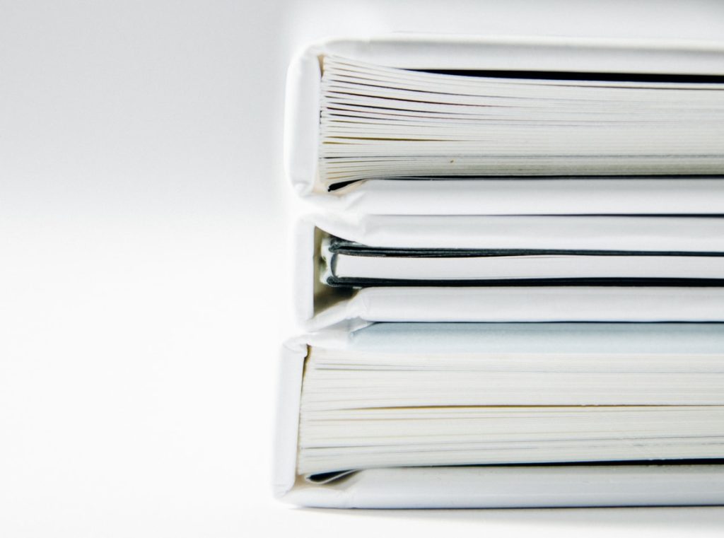 A stack of thick folders on a white surface