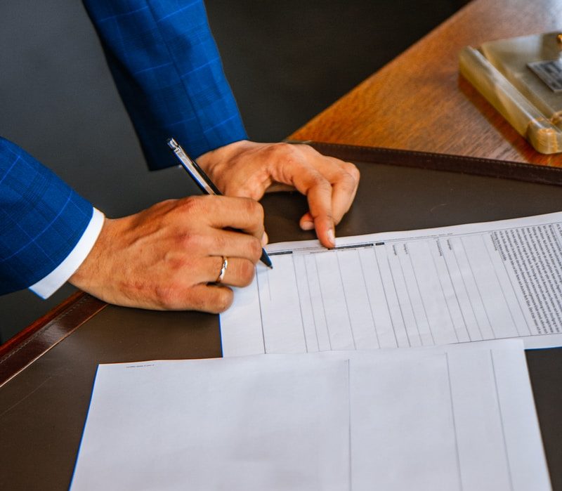 person writing on white form paper