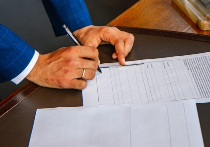 person writing on white form paper