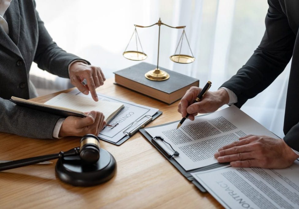 Lawyer, legal advisor, businessman brainstorming information on agreement details Business contracts in legal processing books for accuracy in contract documents. joint financial investment.