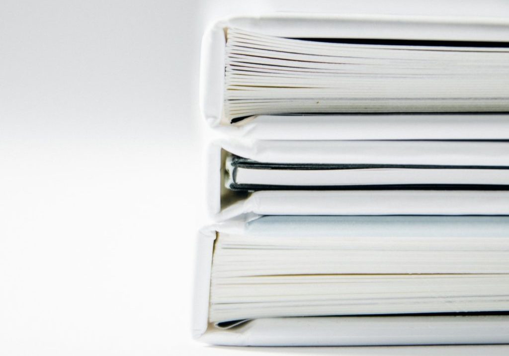 A stack of thick folders on a white surface